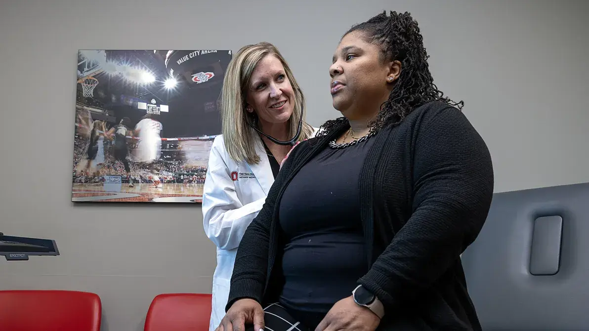 female researcher checking the heart rate of another woman wearing all black