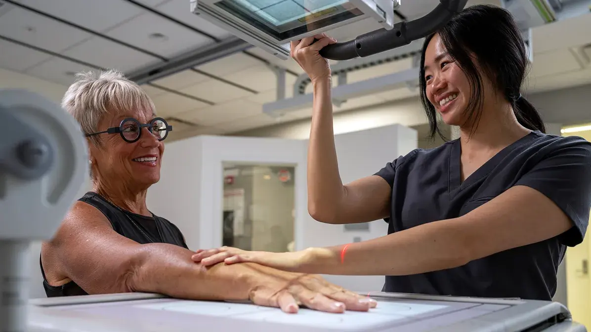 young woman using a medical scanning device on an older woman's arm