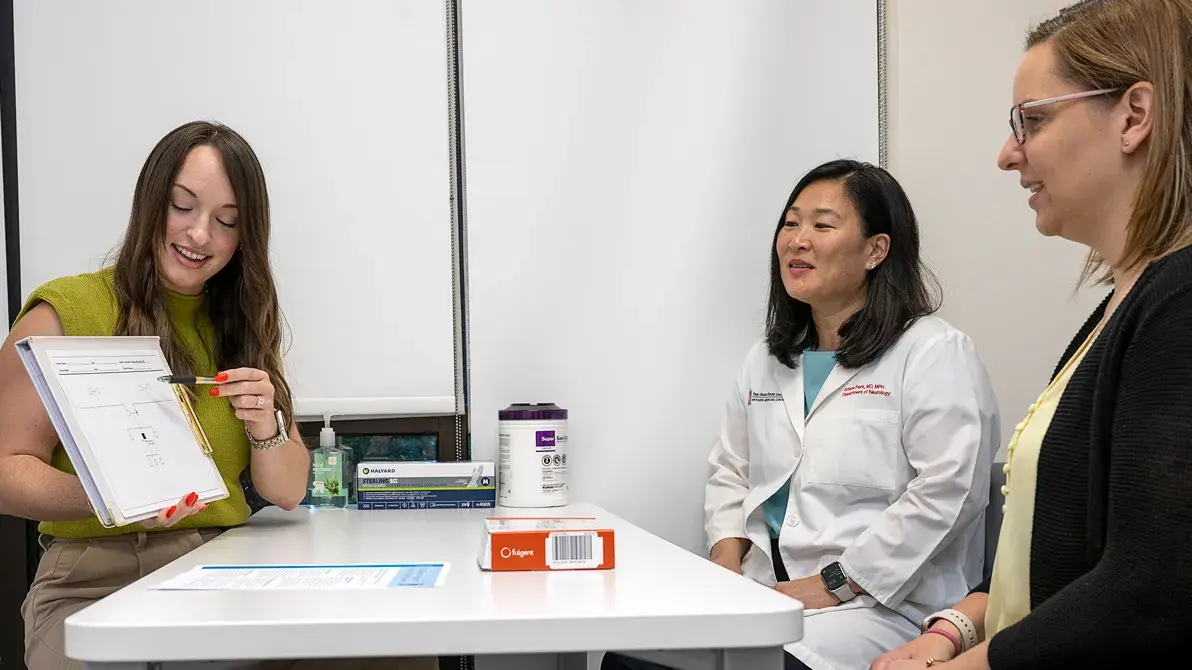 woman shares notes on a small whiteboard with two other women watching