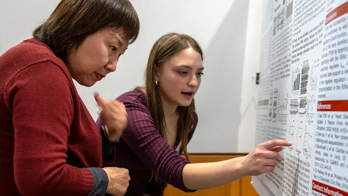 two woman looking at research documentation posted on a whiteboard