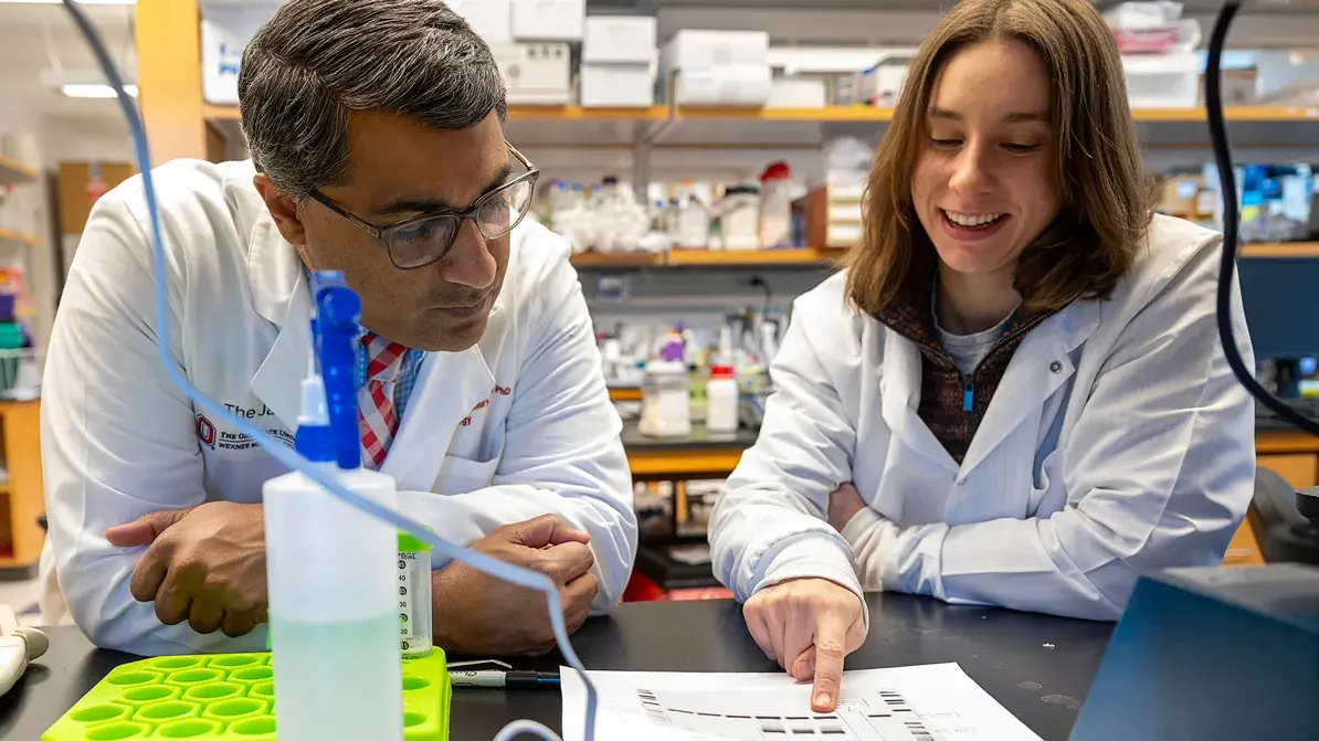 woman shows a fellow collaborator a paper chart in a laboratory setting